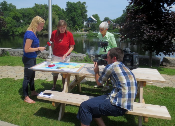 Television and print media were on hand to interview residents about the controversial project, and report on the protest. CBC TV reporter Hillary Johnstone (left) listens as a model of the proposed Enerdu project is explained.
